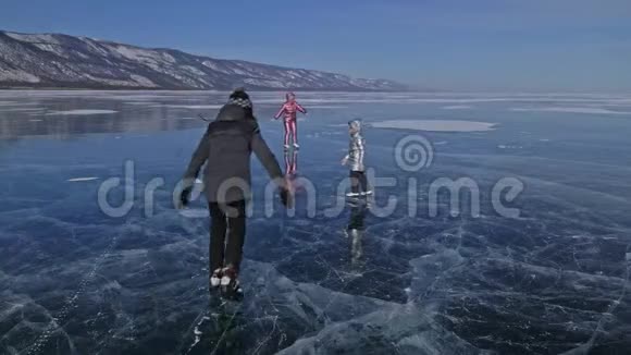 家人白天在滑冰女孩们骑着大自然中的花样冰鞋妈妈女儿和儿子一起骑在冰上视频的预览图