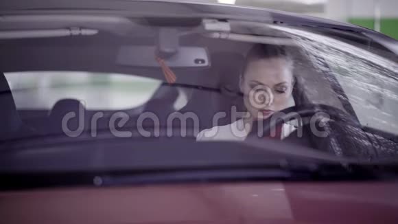 穿着白色衬衫的漂亮女孩坐在方向盘后面的红色汽车上视频的预览图
