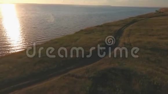 美丽的年轻家庭在阳光和河水的映衬下沿着悬崖奔跑从空中拍摄视频的预览图