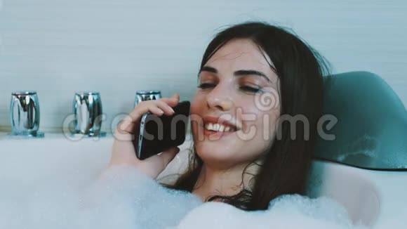 年轻女孩享受充满泡沫的浴室在电话里聊天别紧张休息视频的预览图