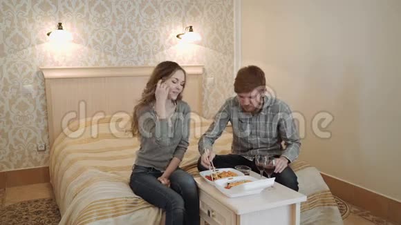 一对年轻夫妇在豪华酒店房间吃寿司从饭盒和喝红酒视频的预览图