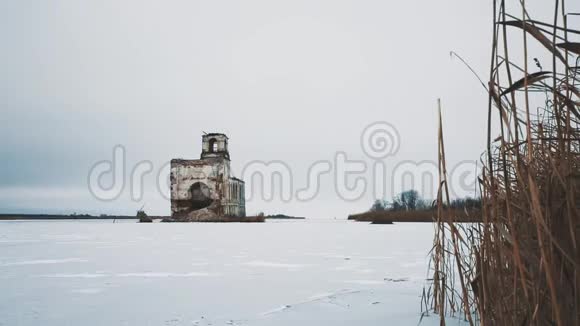 冰雪覆盖的冰冻湖中央废弃的教堂建筑视频的预览图