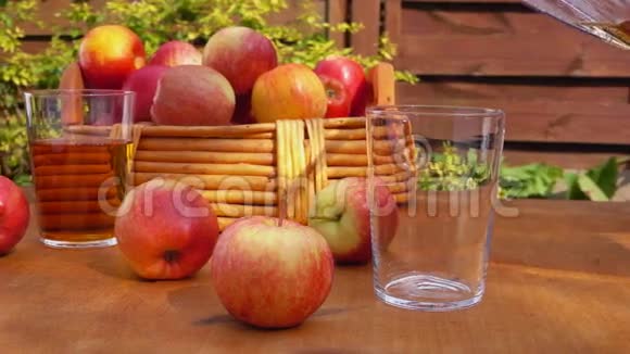 苹果汁和一篮子熟苹果放在木桌上视频的预览图