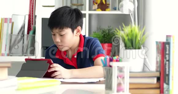 亚洲的青少年用平板电脑做作业表情严肃视频的预览图