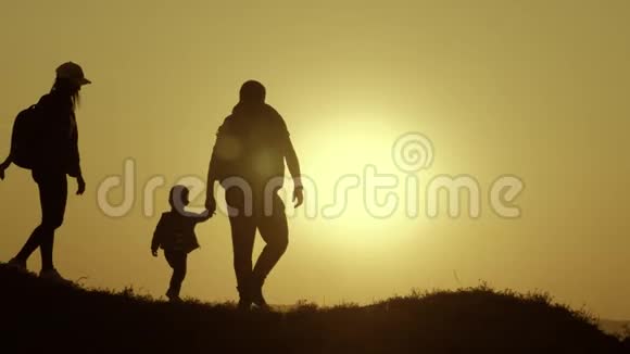 父亲母亲和孩子徒步旅行的剪影婴儿坐在父亲的肩膀上徒步旅行背包旅行者徒步旅行视频的预览图