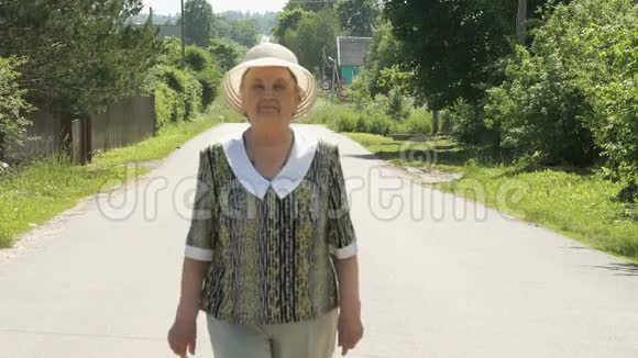 阳光明媚的一天老妇人在路上散步视频的预览图