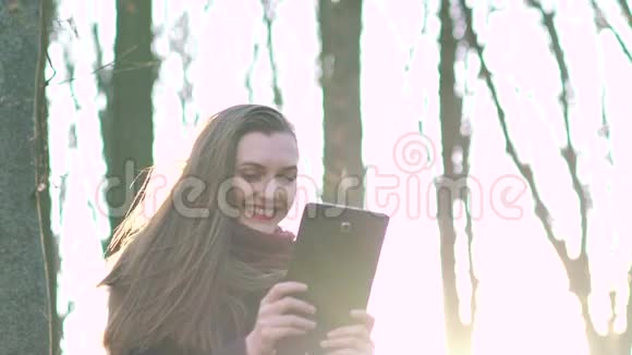 在阳光明媚的森林里拿着平板电脑的女孩慢慢地视频的预览图
