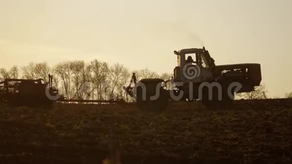 俄罗斯拖拉机夕阳农民剪影以播种机为一部分的土壤改良土地视频的预览图