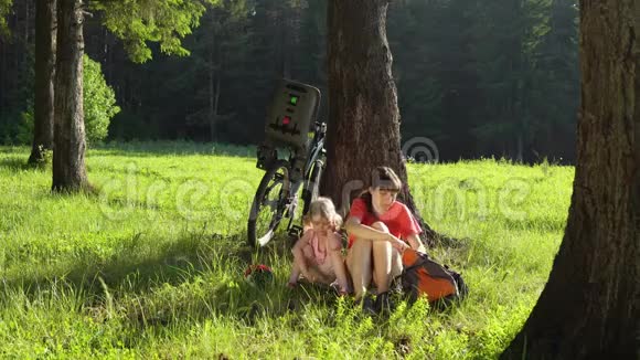 这家人在阳光明媚的日子里骑自行车在夏天的森林里休息视频的预览图