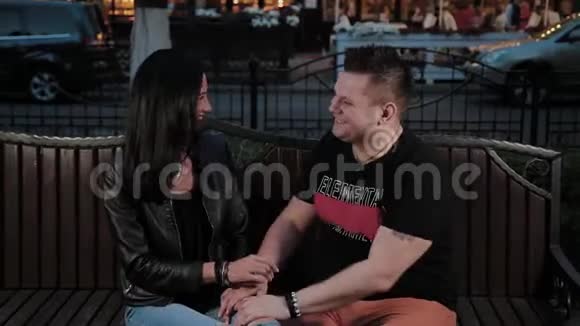 快乐的男人和女人在晚上的长凳上牵手聊天视频的预览图
