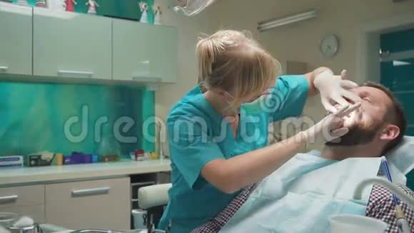 女牙医检查男性病人的牙齿看着相机投中弹视频的预览图