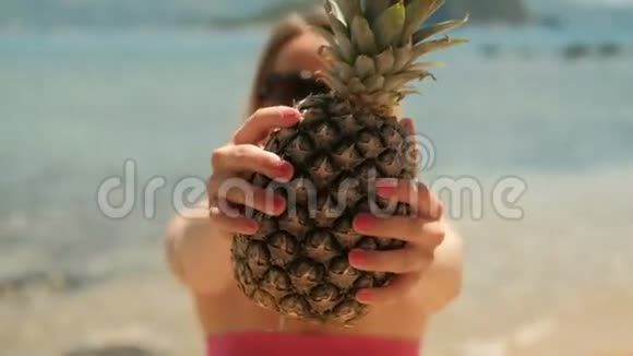 夏天抱着菠萝站在海滩上的年轻女子视频的预览图