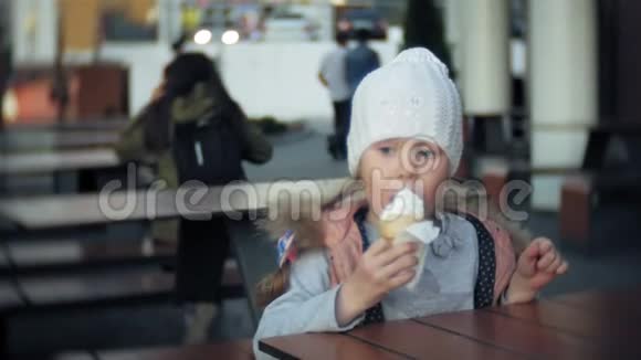 穿白色针织帽子的可爱学步女孩吃冰淇淋视频的预览图