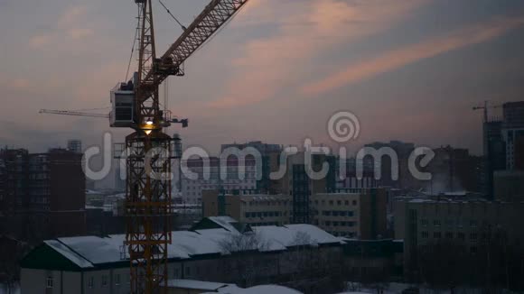 冬季黄昏时分在建筑工地的吊车工作4k视频的预览图