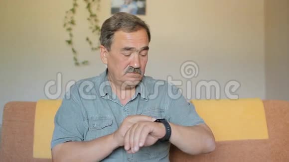 老人摸着智能手表他坐在家里的沙发上查看留言视频的预览图