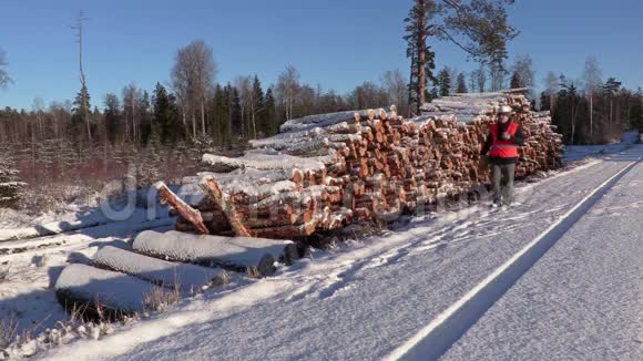 伐木工用绳子和斧头在一堆原木附近行走视频的预览图