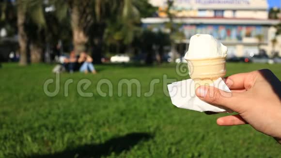 一个男人在街上吃快餐他穿着冰淇淋吃它在城市街道模糊的背景下视频的预览图