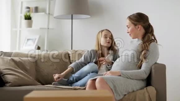快乐的孕妇和女孩在家闲聊视频的预览图