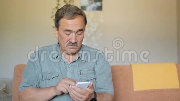 有胡子的老人摸着手机他在社交网络上写道视频的预览图
