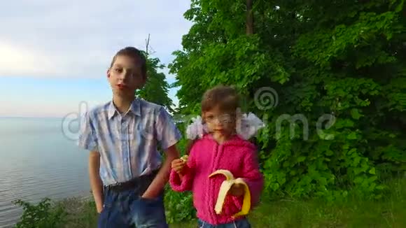 孩子们在一个大湖畔的森林里休息女孩吃香蕉视频的预览图