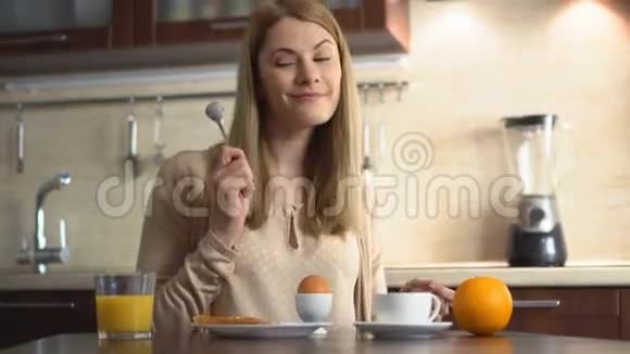 快乐美丽的年轻女人早上在厨房里傻乐唱歌演奏音乐视频的预览图