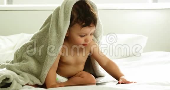 可爱的宝宝头上有毯子玩平板电脑视频的预览图