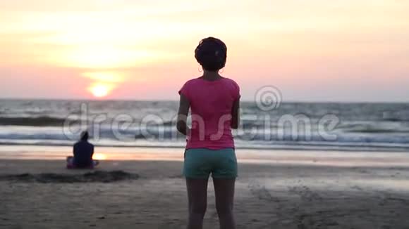 日落时在沙滩上看海洋的女人肖像视频的预览图