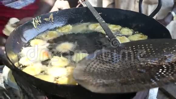 人们把当地的食物放进大煎锅里的热油里视频的预览图