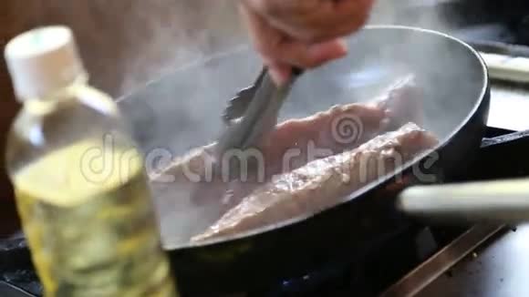 在平底锅上加油和煎鱼的人视频的预览图