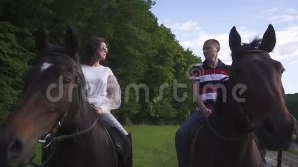 幸福的年轻家庭夫妇一起在绿色公园骑马蓝天背景视频的预览图