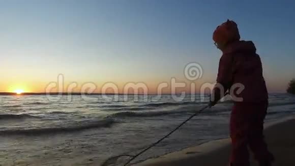 女孩是湖的岸边她正在研究海浪是如何在沙质翻滚的视频的预览图
