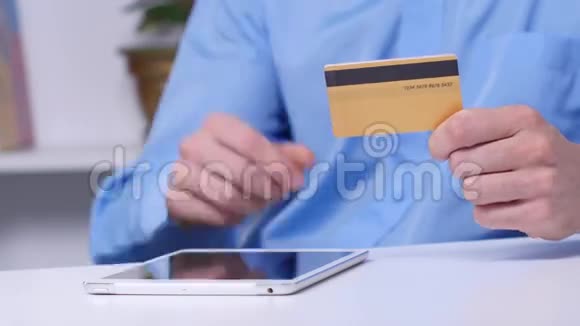 男子网上购物使用数字平板电脑和黄金信用卡网上购物闭合视频的预览图