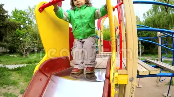 快乐活泼的小男孩在游乐场滑下来视频的预览图