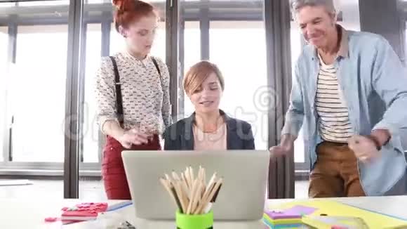 女创意主管向主任和同事展示笔记本电脑项目视频的预览图