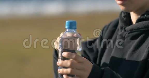 女孩从塑料瓶里喝新鲜的天然水视频的预览图