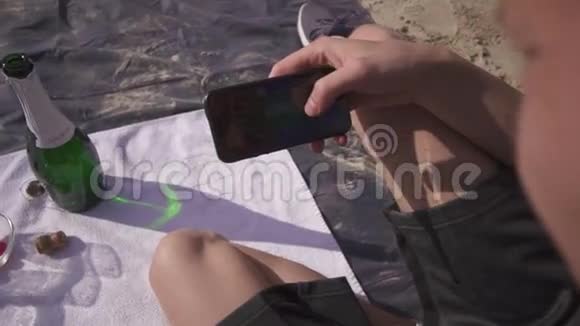 在炎热的夏天可爱的一对在野餐上放松海滩直到男人开始发短信和他的女朋友视频的预览图