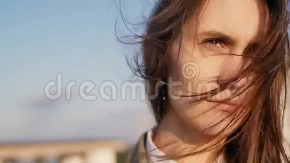 体贴的年轻美丽的女人站在屋顶上的日落她长长的黑发吹着风慢动作视频的预览图