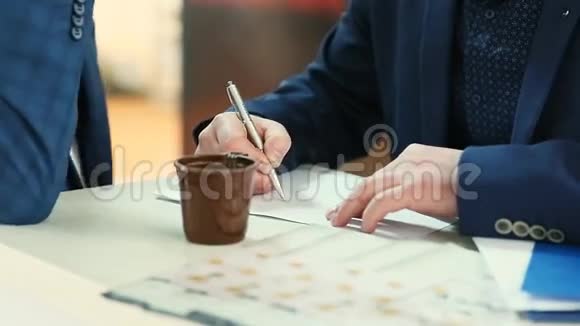 商人用办公工具和咖啡在电脑桌上的笔记本上绘制商业图表视频的预览图