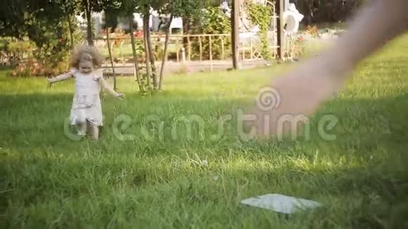 快乐的小女孩穿着白色的裙子在绿色的草地上奔跑视频的预览图