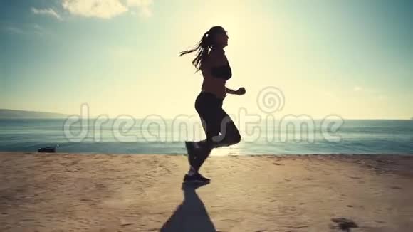 健康的年轻女子日出时在海边奔跑视频的预览图