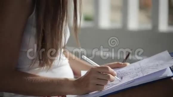 女人坐在阳台上花时间画纸上的圆珠笔视频的预览图