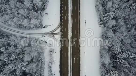 4K在冰冻的冬季森林里驾驶汽车飞越公路高空俯视图视频的预览图