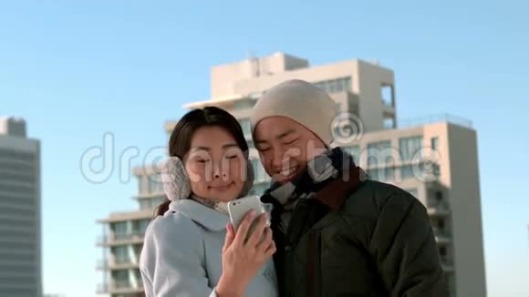 一对用手机穿暖衣服的夫妇视频的预览图