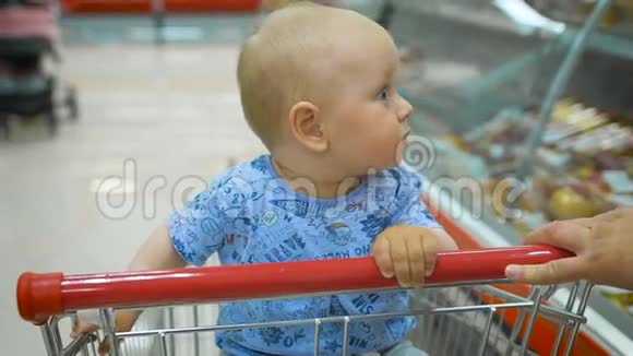 小婴儿坐在超市的购物车里而他的父亲选择购买视频的预览图