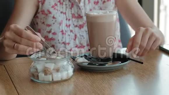 快乐的女孩喝咖啡在咖啡馆里放松微笑着看着智能手机视频的预览图