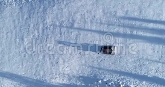 冬季滑雪场斜坡上雪猫或雪修复者的高空俯视图视频的预览图