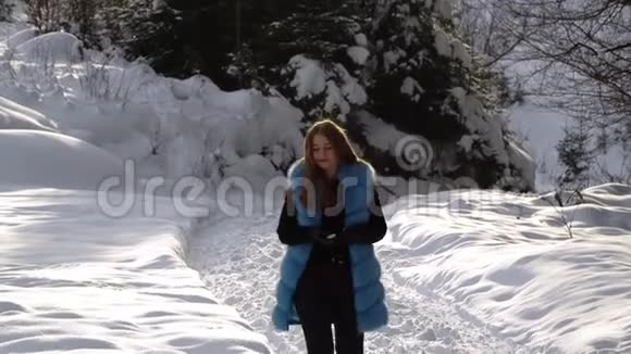 年轻漂亮的女孩走在白雪皑皑的冬林里她快乐而平静女孩看着两边太阳是视频的预览图