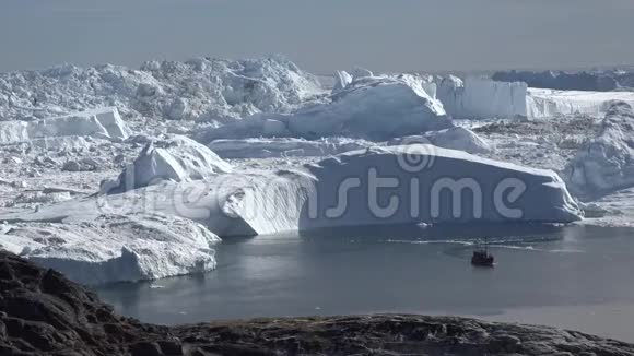 一艘小船沿着巨大的冰山航行视频的预览图