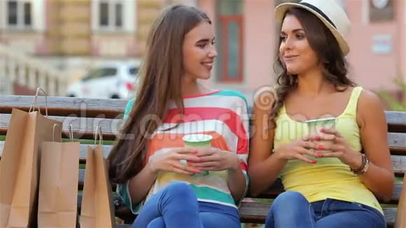 两个坐在长凳上喝咖啡的女孩视频的预览图