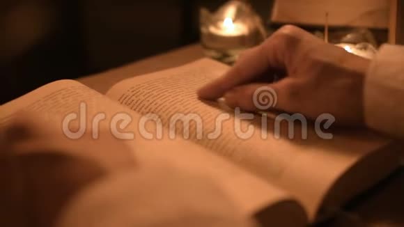 大特写女魔术师在一个黑暗的房间里烛光在寻找一本书中的咒语低键带电摄像机神秘视频的预览图